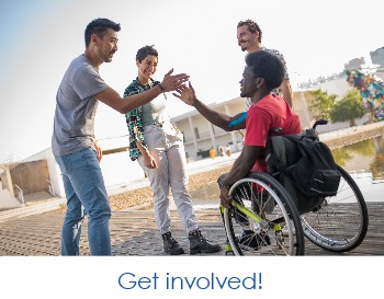 Get involved! Multicultural people, one in a wheelchair, handshaking by a waters edge.