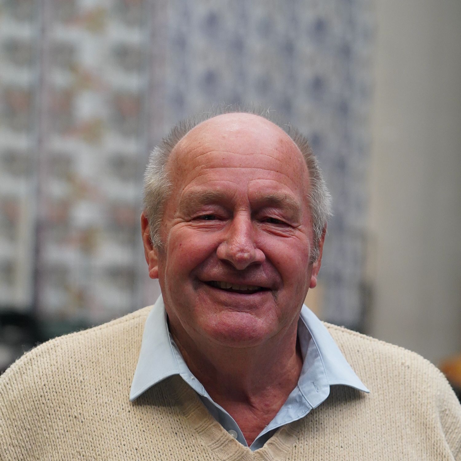 Carl Jones - an older gentleman with balding grey hair. He is wearing a beige jumper covering a light blue shirt.