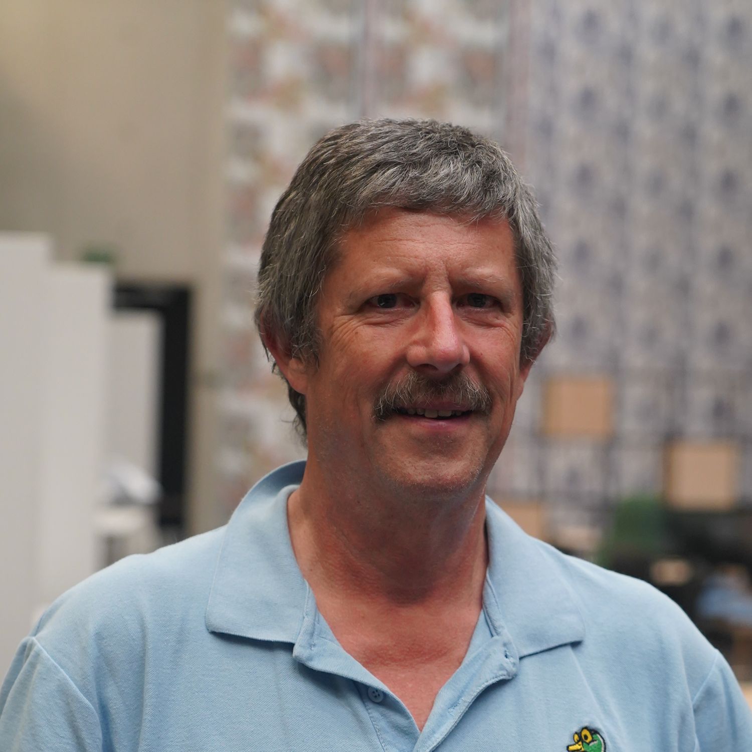 Tim Clarke - middle-aged man with short greying hair wearing a blue top.