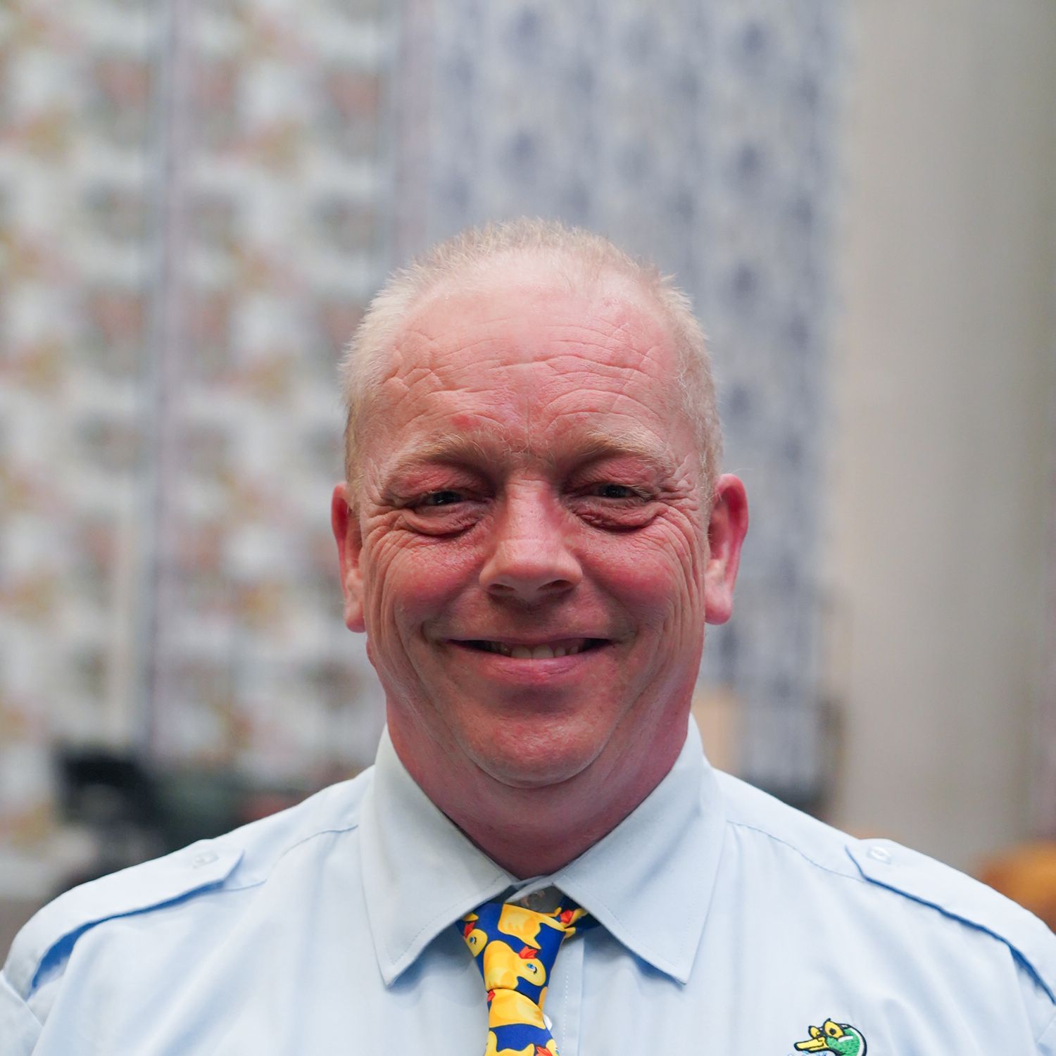 Tim Sedge - a middle aged, balding man wearing a light blue top with yellow tie.